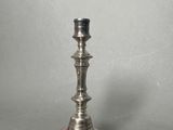 an antique silver plated candle holder on a grey background