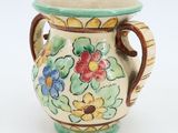 a small vase with flowers painted on it on a white surface