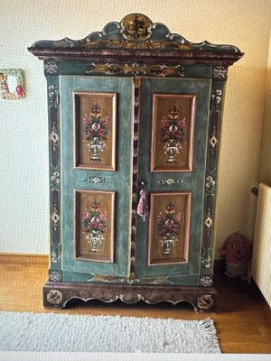 une armoire verte décorée de tableaux, placée dans un coin de la pièce