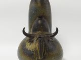 un vase marron orné de cornes, posé sur un fond blanc