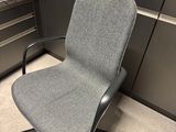 une chaise de bureau avec une étiquette à l'arrière, dans un box