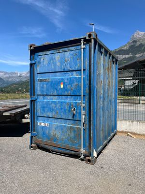 un conteneur bleu posé au milieu d'un parking