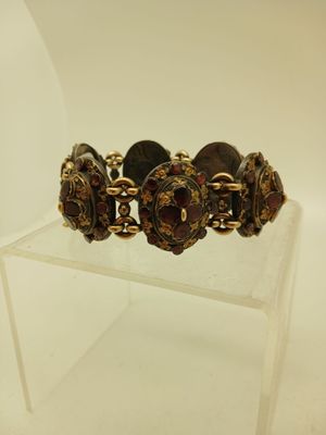 bracelet doré et marron posé sur un socle en acrylique transparent, sur fond blanc