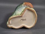 a figurine of a shell with a green leaf on it
