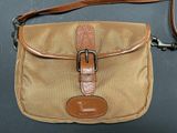 an image of a tan purse with a brown strap on a black surface