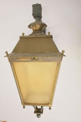 an old fashioned light hanging from the side of a wall