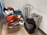 un tas de vêtements posé par terre à côté d'une poubelle