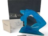 an image of a blue sculpture sitting next to a box and a piece of chocolate