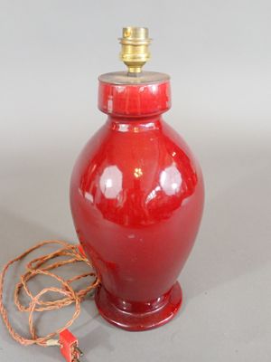 a red vase with a rope around it and a light on top