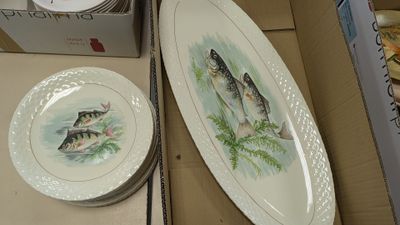 two plates with fish painted on them sitting on a table