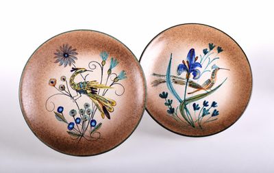 pair of decorative plates with birds and flowers on them on a white surface