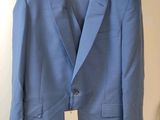 a blue suit hanging on a hanger in a room
