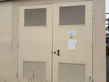 deux portes situées sur le côté d'un bâtiment sur lequel est accrochée une enseigne