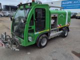 un camion de nettoyage des rues, de couleur verte, garé sur un parking