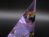 un gros plan d'un objet de forme triangulaire posé sur une surface noire