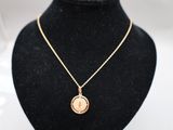 un collier en or orné d'une pièce de monnaie, sur un mannequin noir
