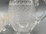 four glasses and a pitcher sitting on a table