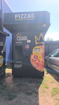 two vending machines in front of a building that has pizzas on it