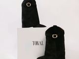 deux paires de bottes en daim noir, accompagnées d'une boîte blanche posée sur un fond blanc