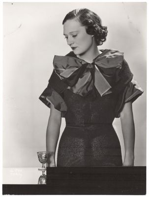 photographie en noir et blanc d'une femme portant une robe ornée d'un nœud