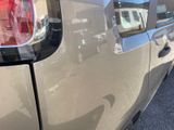 the rear end of a silver car with a reflection of a house in the window