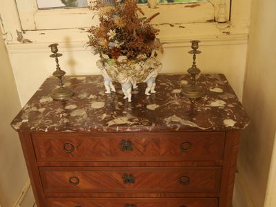 une commode au plateau en marbre, sur laquelle est posé un vase