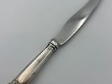 an antique silver plated knife on a white surface