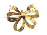 gold bow brooch with diamonds on it on a white background