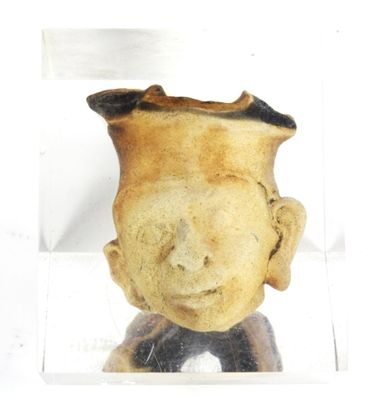 un petit vase orné d'un visage, dans une boîte transparente
