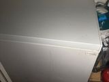 a silver refrigerator in the corner of a room with a fire extinguisor