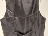 the back of a black vest hanging on a white wall
