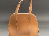 an image of a tan leather handbag on a gray background