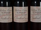 three bottles of red wine are lined up on a shelf