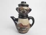 a black and white teapot with a painting on it