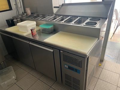 stainless steel counter top in a commercial kitchen with a sink and freezer