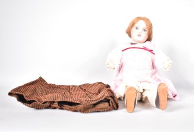 a doll sitting next to a blanket on a white surface