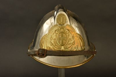 un casque orné d'une pièce d'or, posé sur un socle