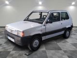 une petite camionnette blanche garée sur un sol à damier