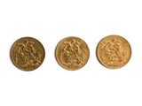 trois pièces d'or sont alignées sur une surface blanche