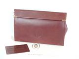 pochette en cuir marron avec des finitions dorées et une étiquette sur fond blanc