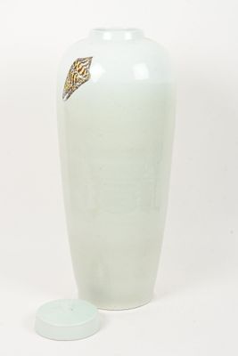 a large white vase with a gold leaf on it