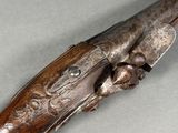 a close up of a rifle with a wooden handle on a gray surface