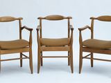 trois chaises en bois assises l'une à côté de l'autre sur une surface blanche