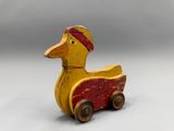 yellow and red wooden toy duck with red bandanna on its head