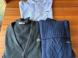 three sweaters are laid out on a wooden table in front of a shelf