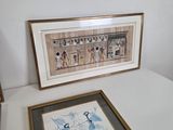 two framed pictures on a table with a picture of a woman in a blue dress