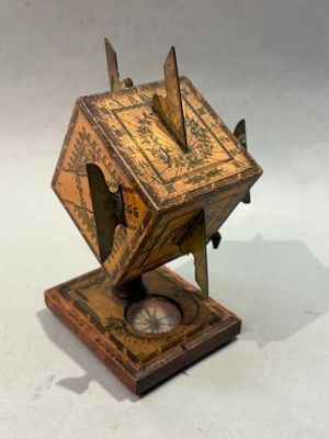 une petite horloge en bois posée sur un socle, sur une surface blanche
