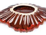 a red glass vase with a gold rim on a white surface