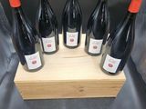 six bouteilles de vin rouge dans un coffret en bois sur fond gris
