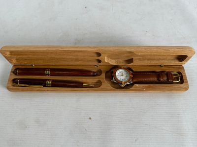 a wooden box with a watch and pen in it